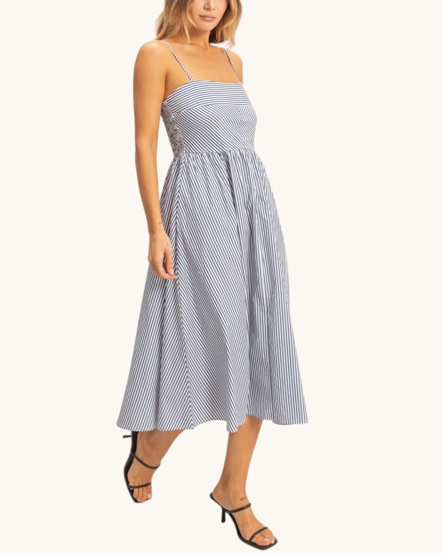Woman wearing a blue and white striped midi dress on a white background.