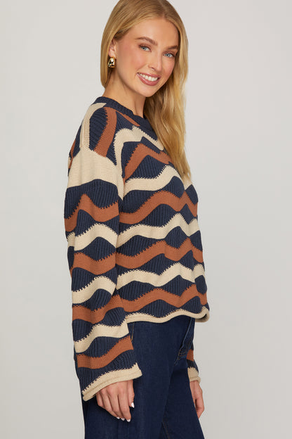 Side view of model wearing ivory, navy, and cinnamon wave stripe knit sweater showing dropped shoulders, relaxed fit, and rolled cuffs.