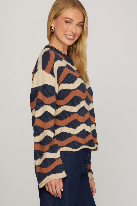 Side view of model wearing ivory, navy, and cinnamon wave stripe knit sweater showing dropped shoulders, relaxed fit, and rolled cuffs.