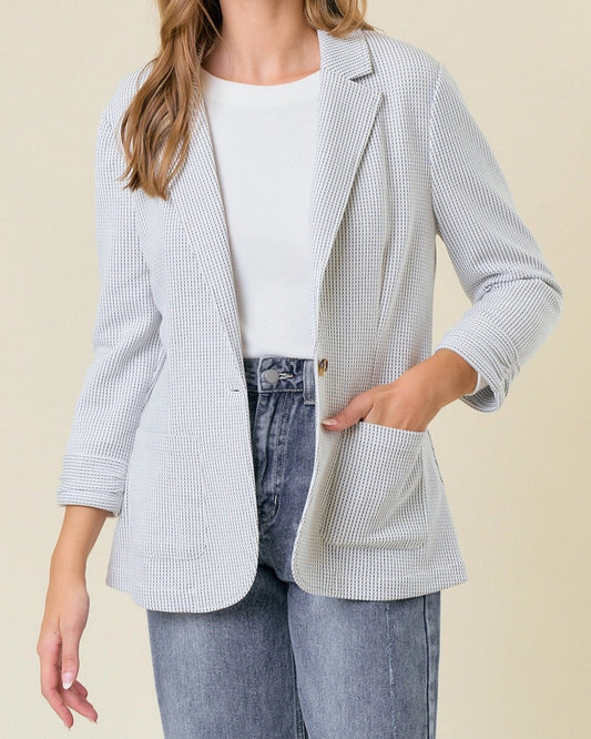Off-white ribbed knit blazer with shirred sleeves and single-button closure.