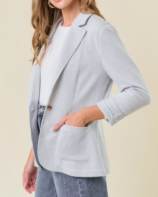 Off-white ribbed knit blazer with shirred sleeves and single-button closure. 