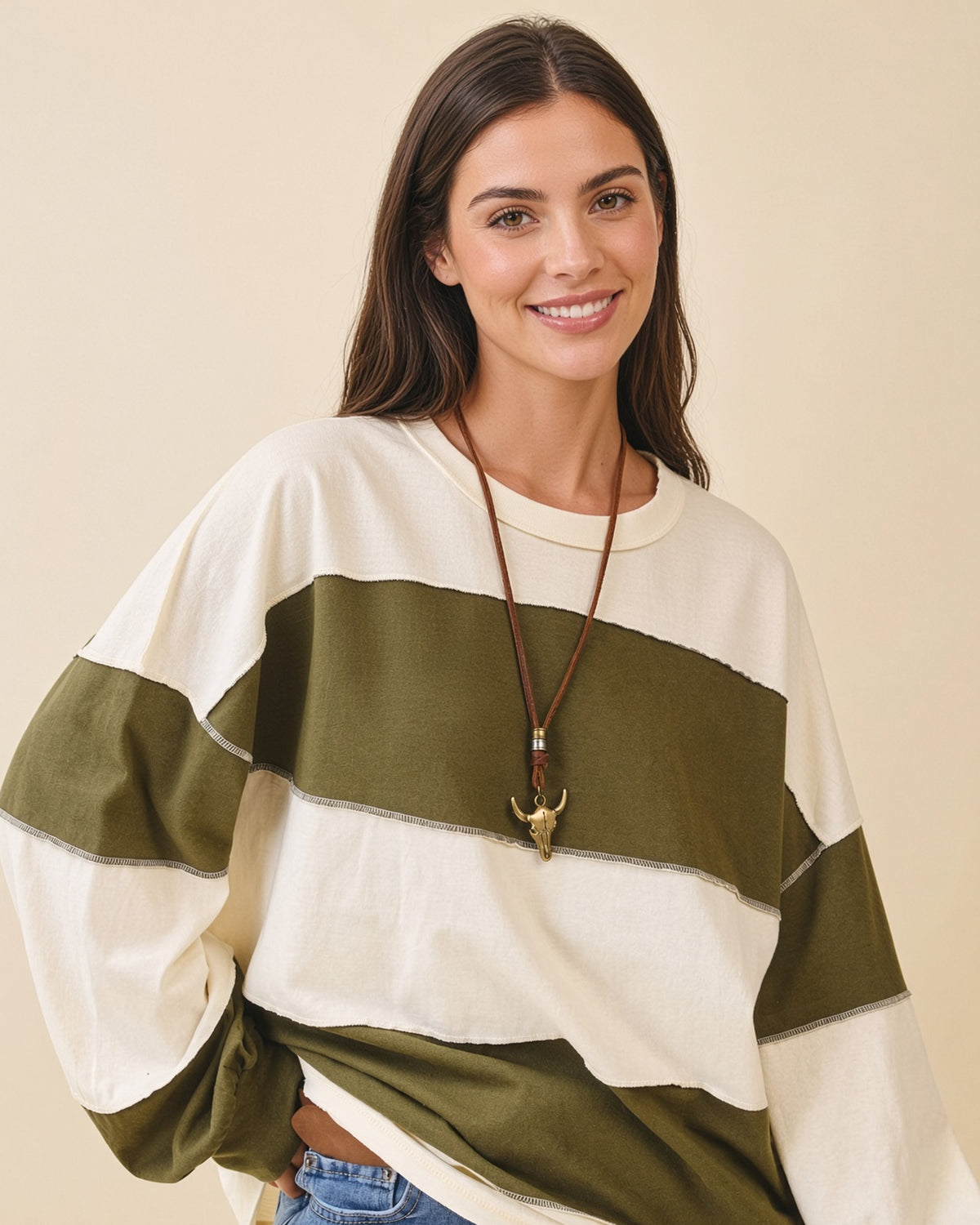 Model wearing a relaxed fit long sleeve top with crew neck, wide olive and butter color blocks and exposed seams.