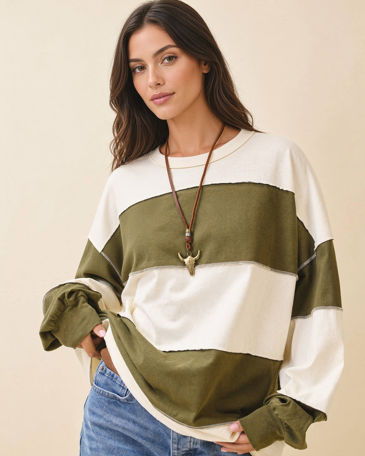 Model wearing a relaxed fit long sleeve top with crew neck, wide olive and butter color blocks and exposed seams.