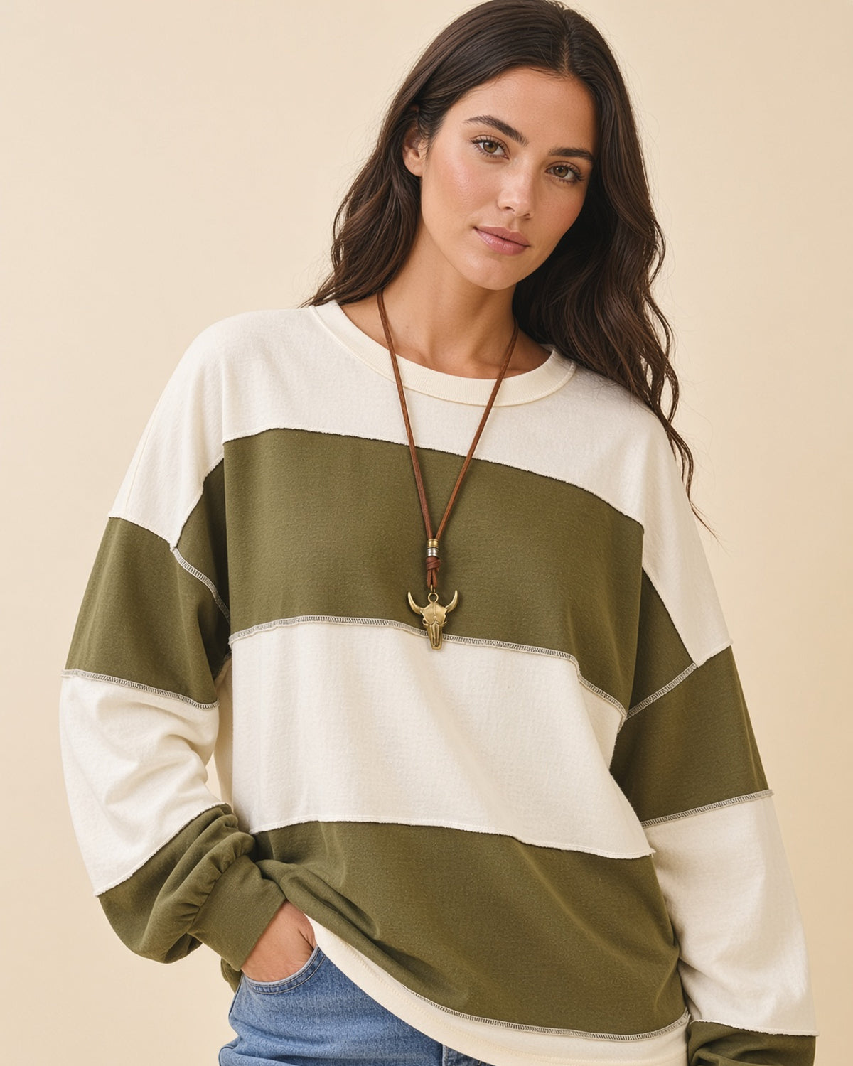 Model wearing a relaxed fit long sleeve top with crew neck, wide olive and butter color blocks and exposed seams.