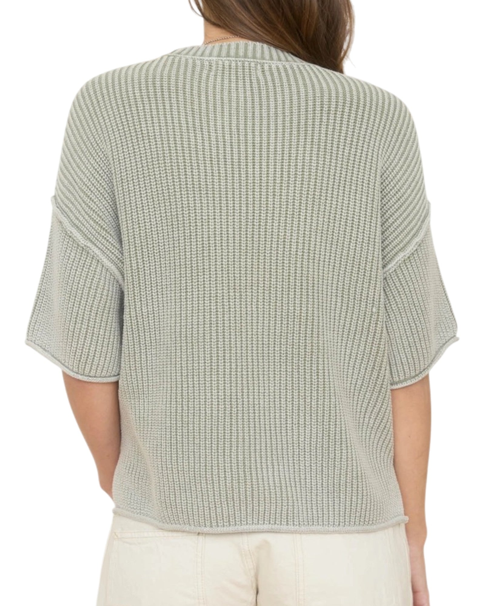 Woman wearing a light green washed short sleeve knit sweater on a white background.