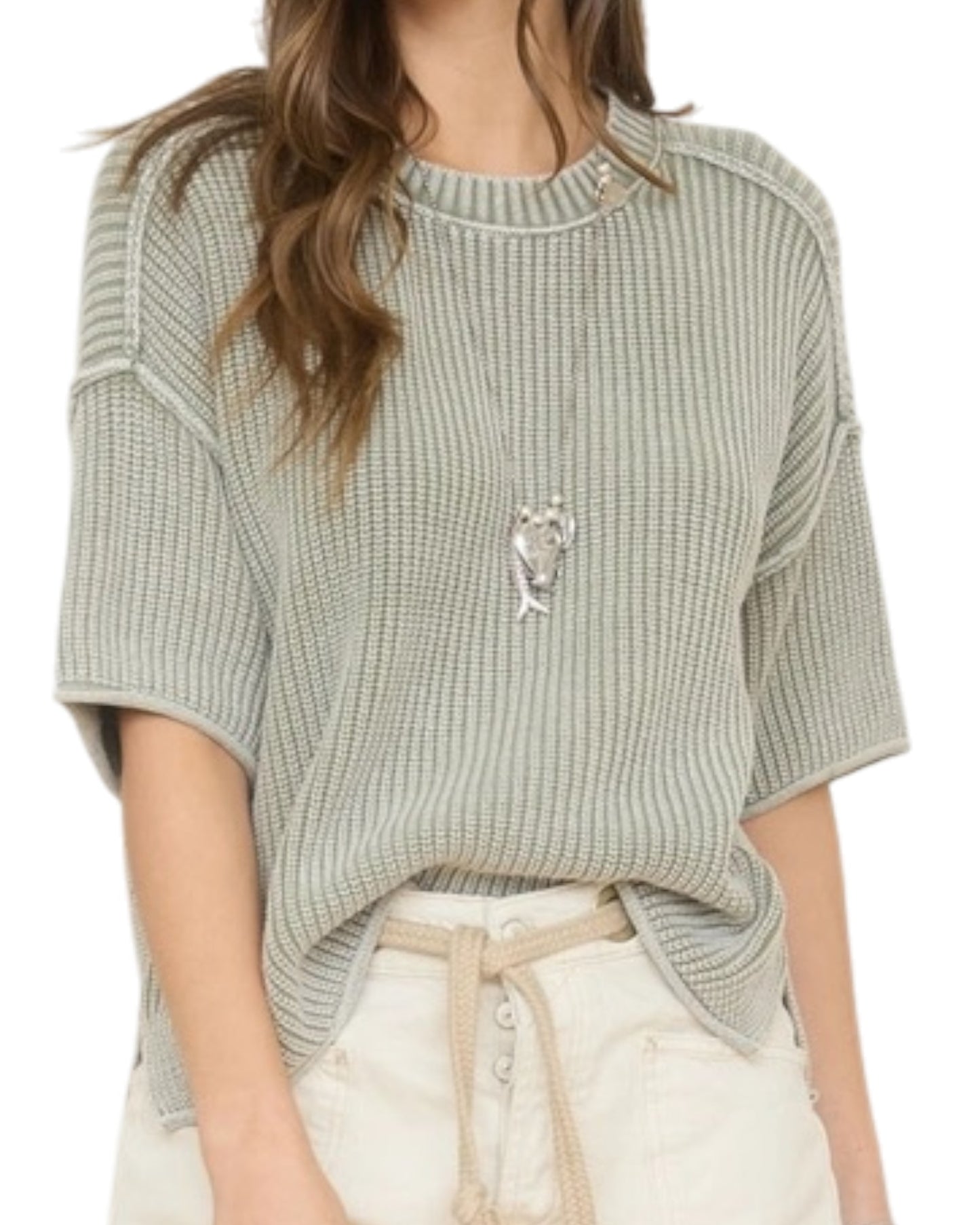 Woman wearing a light green washed short sleeve knit sweater on a white background.