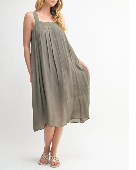 Woman wearing an Olive Green square neck midi dress with wide straps and pleats.