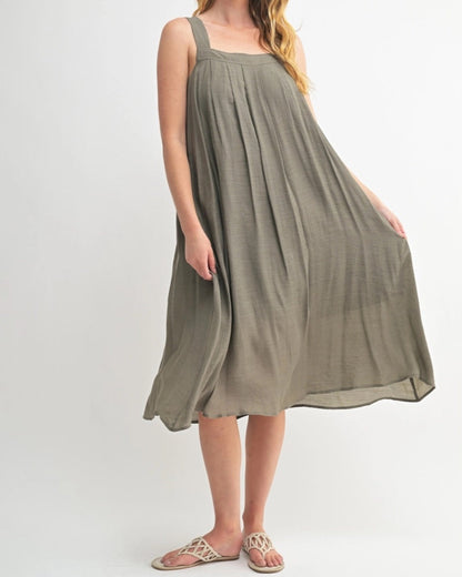 Woman wearing an Olive Green square neck midi dress with wide straps and pleats.