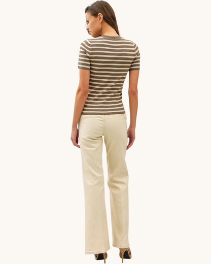 Woman wearing a striped short sleeve shirt and beige pants on a white background.