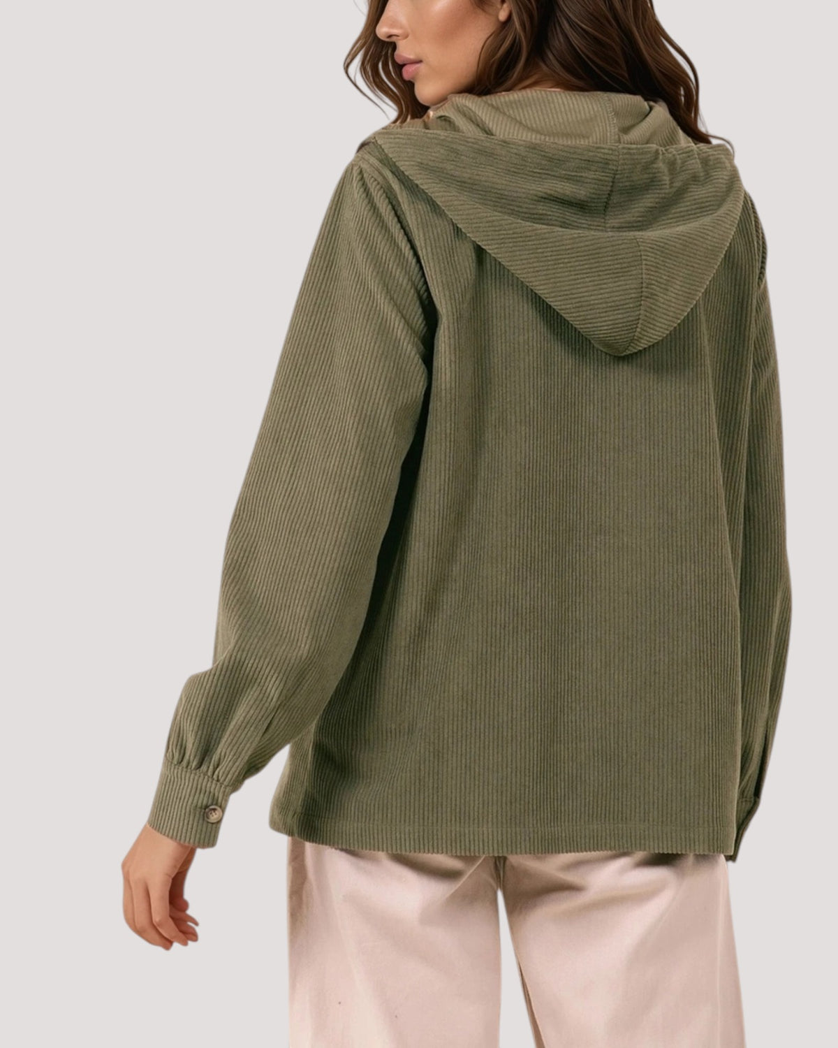 A back view of a woman wearing an olive green corduroy hooded jacket, shown from the back against a light gray studio background.