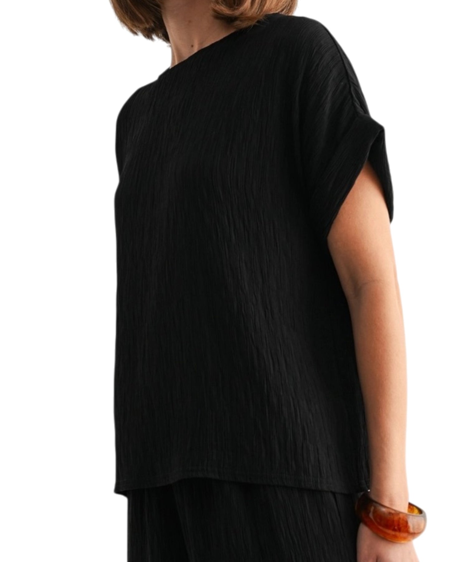 Black woven and textured short sleeve top worn by a person on a white background.