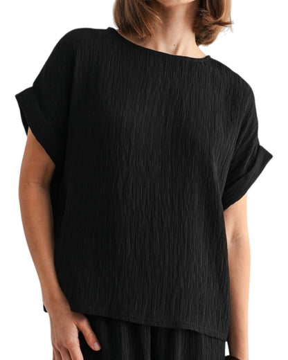 Black woven and textured short sleeve top worn by a person on a white background.