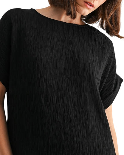 Black woven and textured short sleeve top worn by a person on a white background.