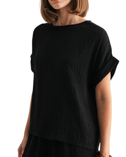 Black woven and textured short sleeve top worn by a person on a white background.