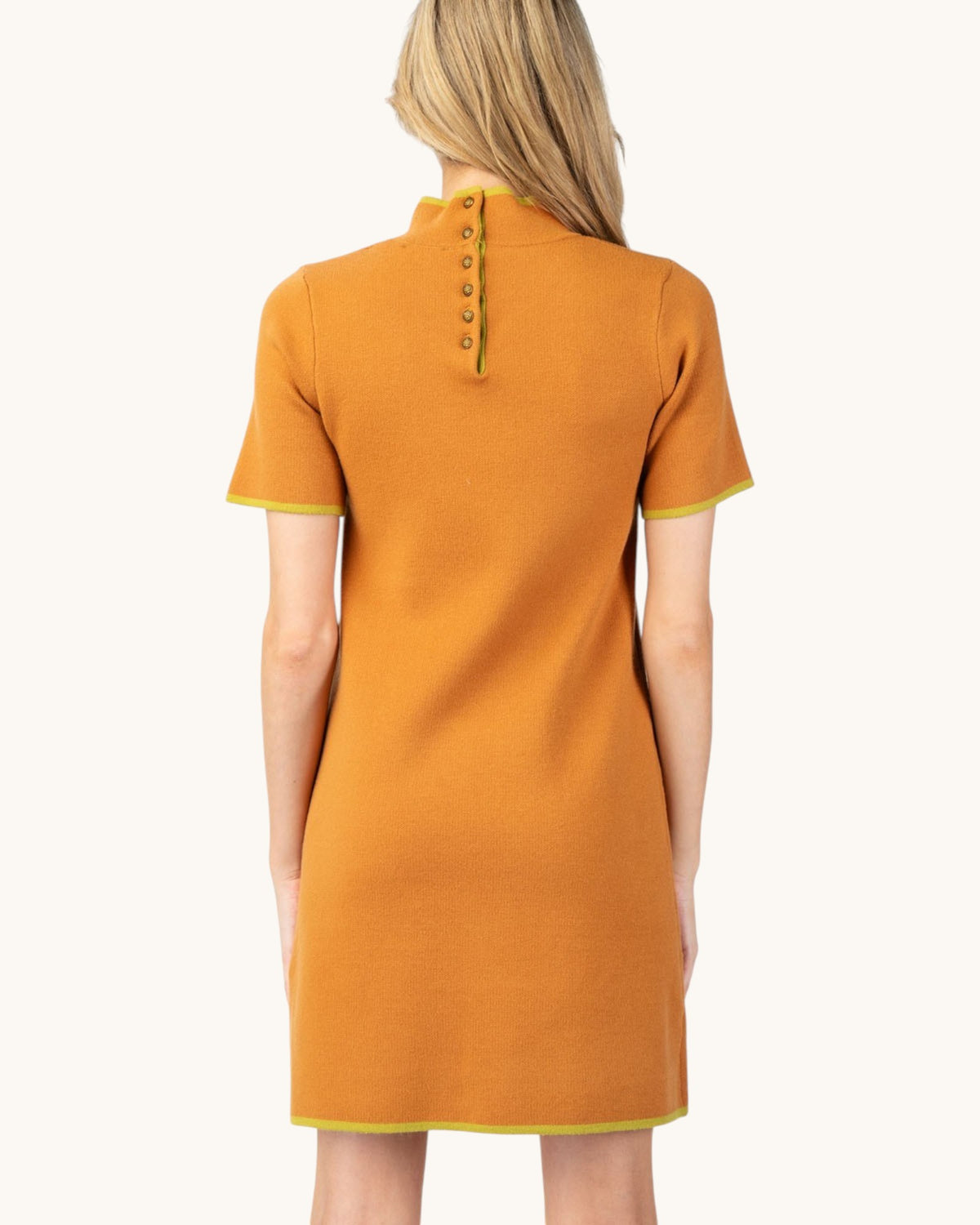 Back view of a model wearing a ginger short sleeve mock neck mini sweater dress with button up back.