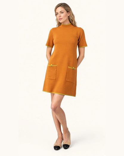 Model wearing a ginger short sleeve mock neck sweater dress with lime contrast trim and front patch pockets with tan and black ballet shoes.