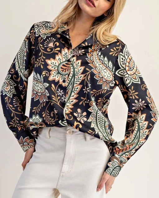 Woman wearing a paisley patterned blouse with long sleeves against a plain background.