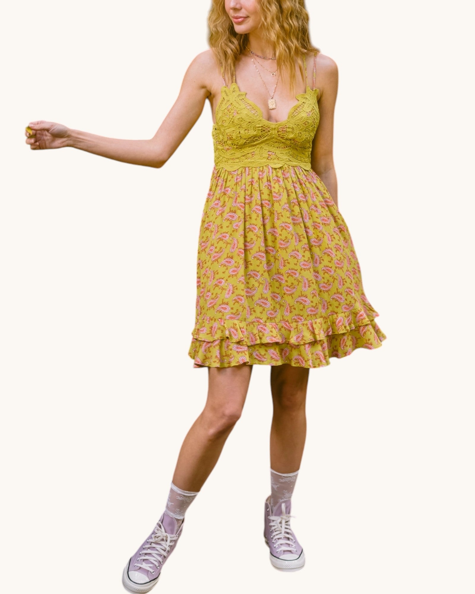 Woman wearing a olive floral dress with pink shoes on a white background.