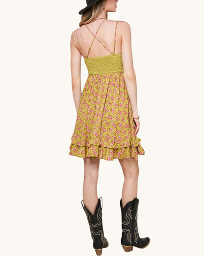 Woman wearing a olive floral dress with cowboy boots on a white background.