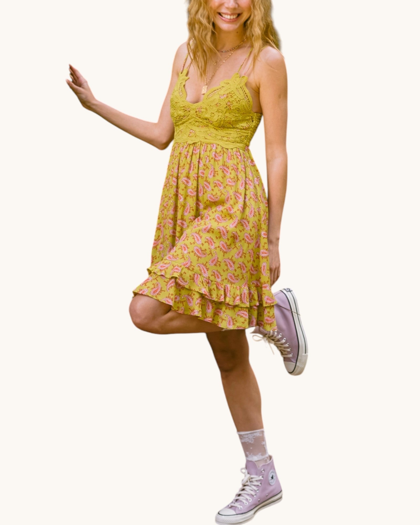 Woman wearing a olive floral dress with pink shoes on a white background.