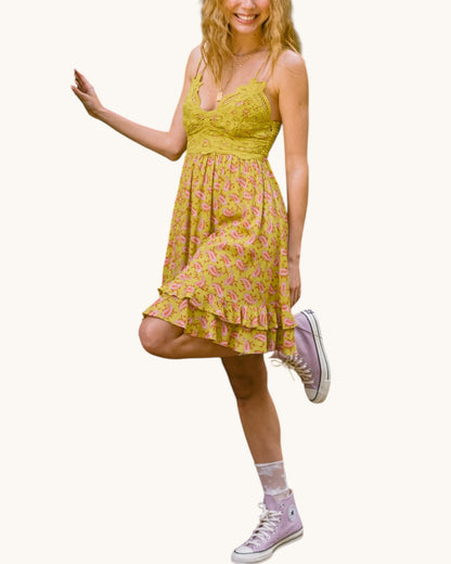 Woman wearing a olive floral dress with pink shoes on a white background.