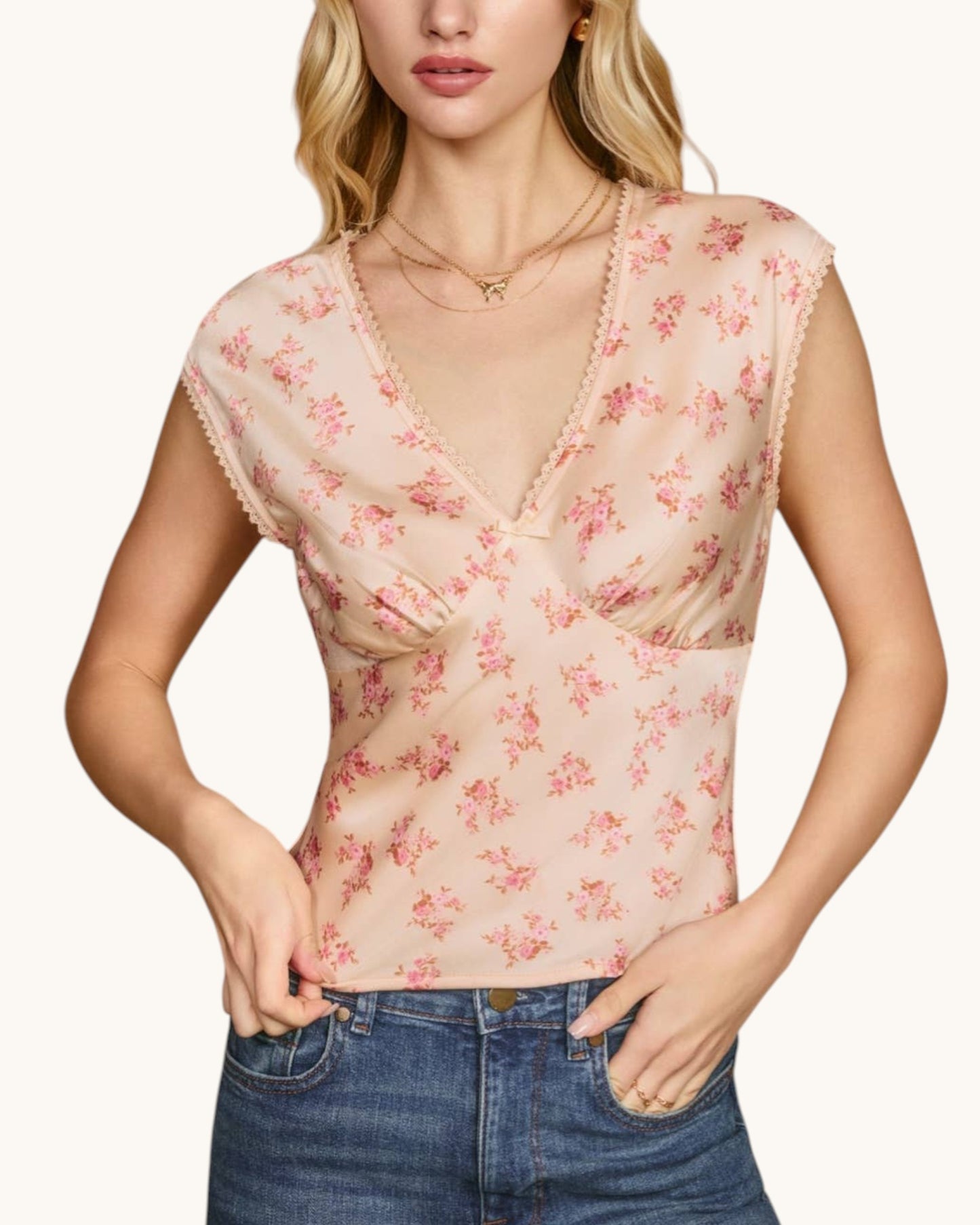 Woman wearing a floral sleeveless top with a plain background.