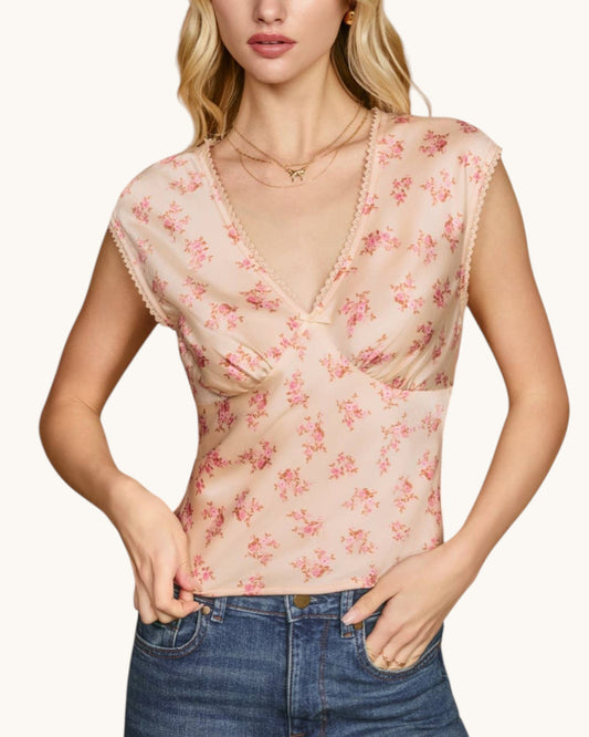 Woman wearing a floral sleeveless top with a plain background.
