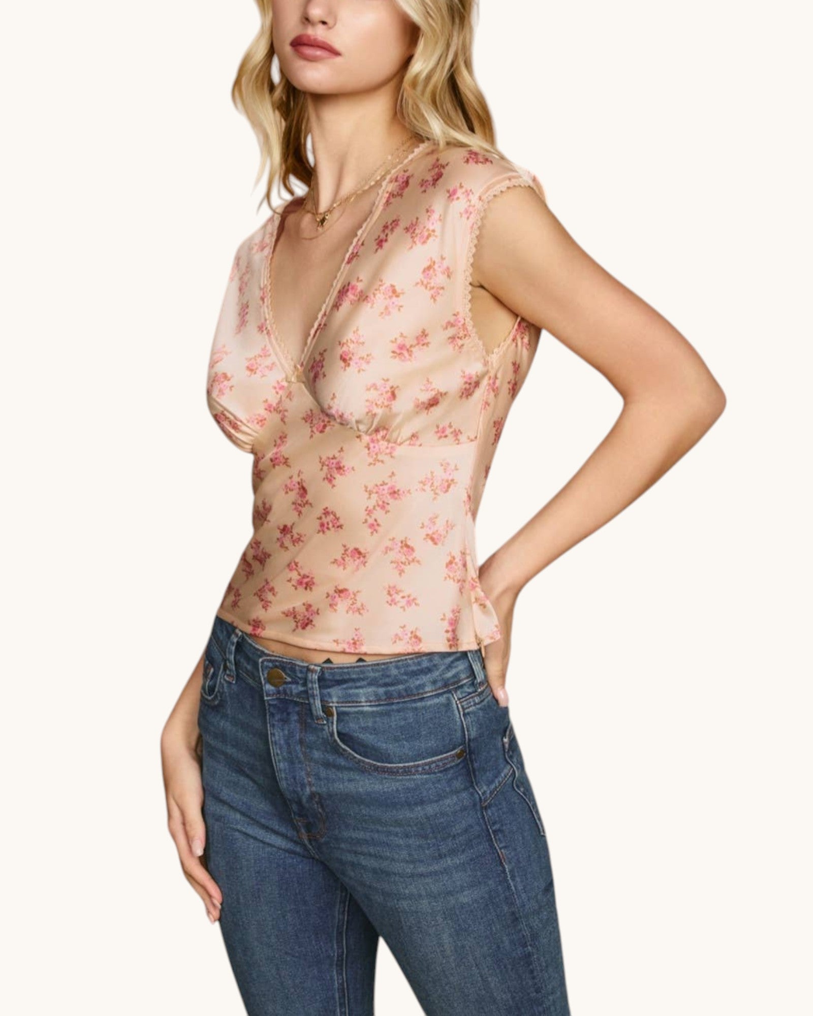Woman wearing a floral top and blue jeans on a white background.