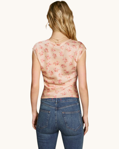 Woman wearing a floral top and jeans on a white background.