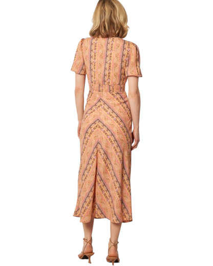 Woman wearing a patterned dress on a white background.