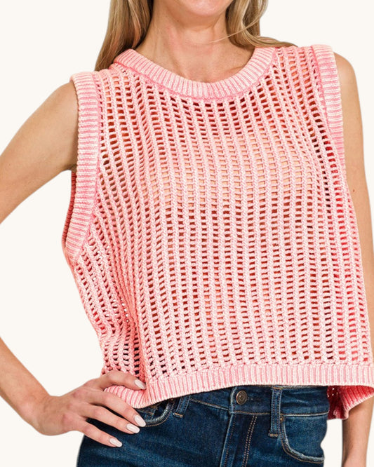 Woman wearing a pink knitted sleeveless top with a white background.