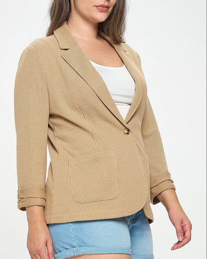 Woman wearing a beige blazer over a white top and blue shorts on a white background.
