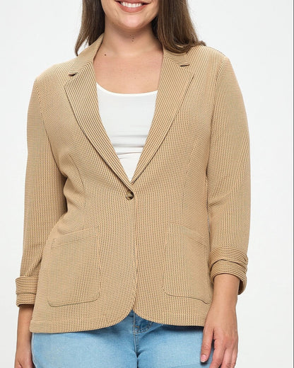 Woman wearing a beige blazer over a white top and blue shorts on a white background.