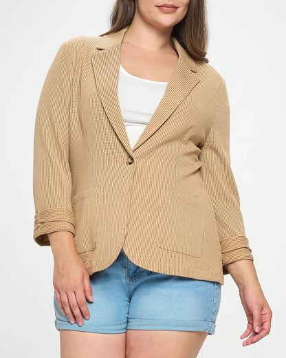 Woman wearing a plus-size beige blazer over a white top and blue shorts on a white background.