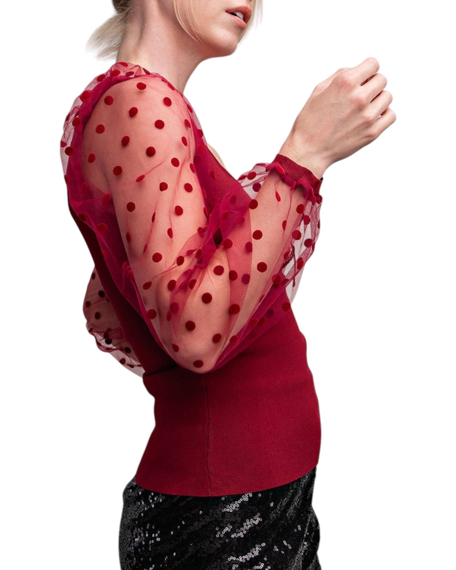 Woman wearing a merlot colored top with long, sheer sleeves with velvet polka dots. 