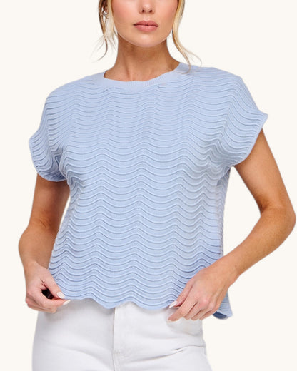 Close up of the Powder Blue short sleeve top with delicate wave pattern paired with white denim. 