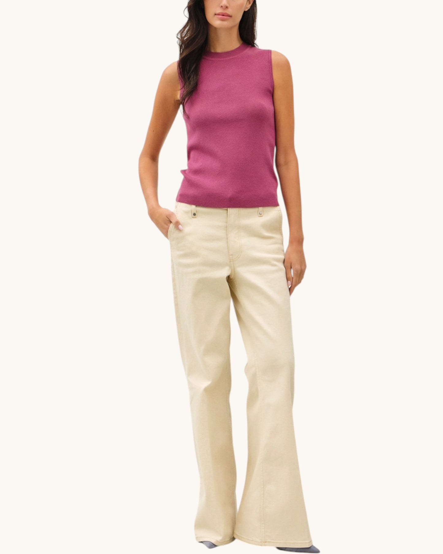 Woman wearing a mauve sleeveless top and beige pants on a white background.