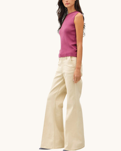 Woman wearing a Mauve sleeveless sweater top and beige flared pants on a white background.
