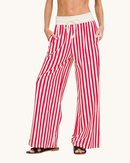 Red and white vertically striped wide-leg pants with an off-white elastic drawstring waistband, modeled on a person against a light cream background.