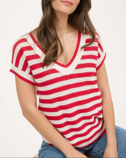 Woman wearing a v-neck red and white striped crochet top on a white background.