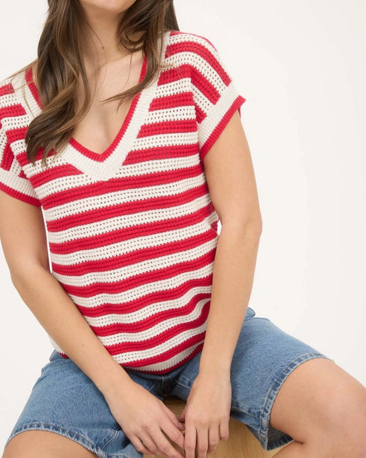 Woman wearing a red and white striped crochet top with denim shorts on a white background.