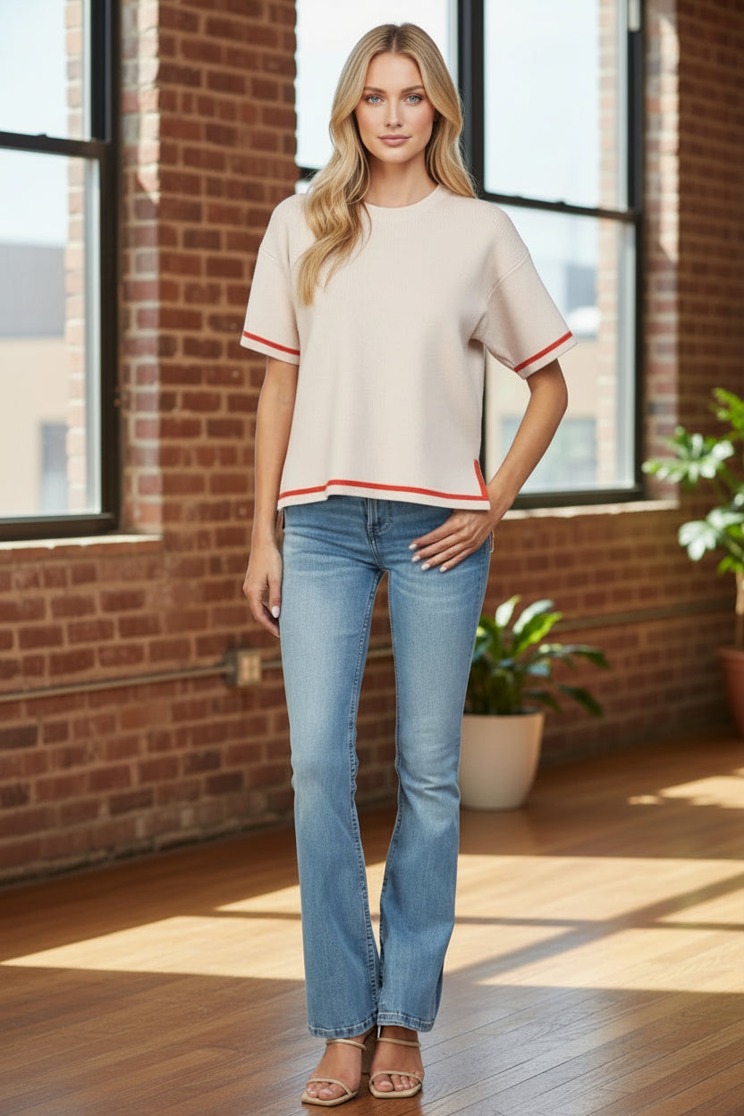 Women wearing jeans and beige short sleeve shirt with red stripe at hem.