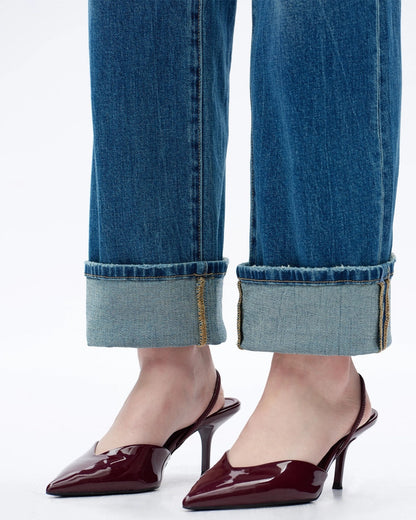 Cuffed blue jeans with burgundy high-heeled shoes on a white background.