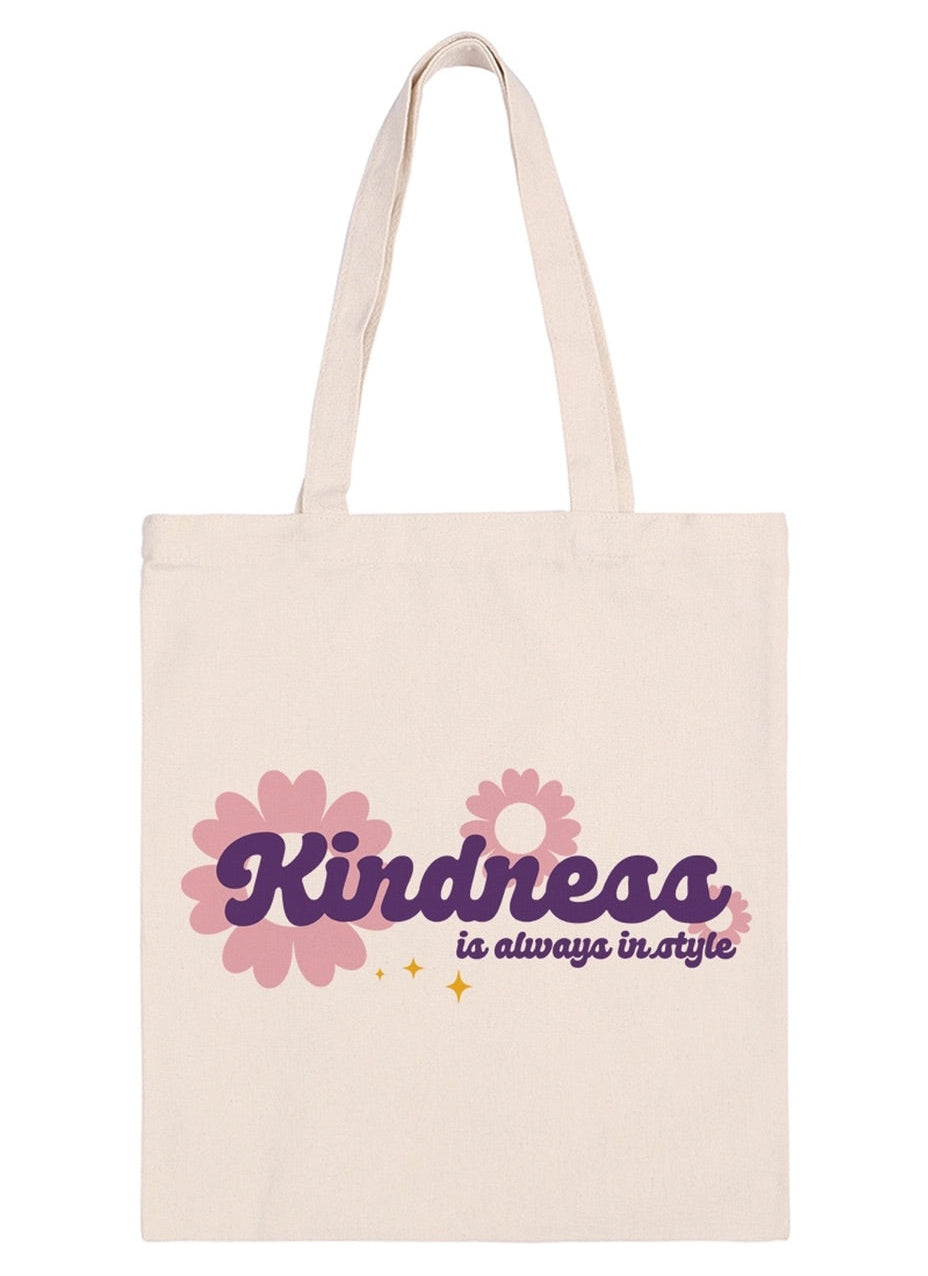 Beige tote bag with 'Kindness is always in style' text and floral designs on a white background.