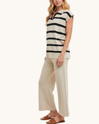 Woman wearing a black and beige striped top and beige pants on a white background.