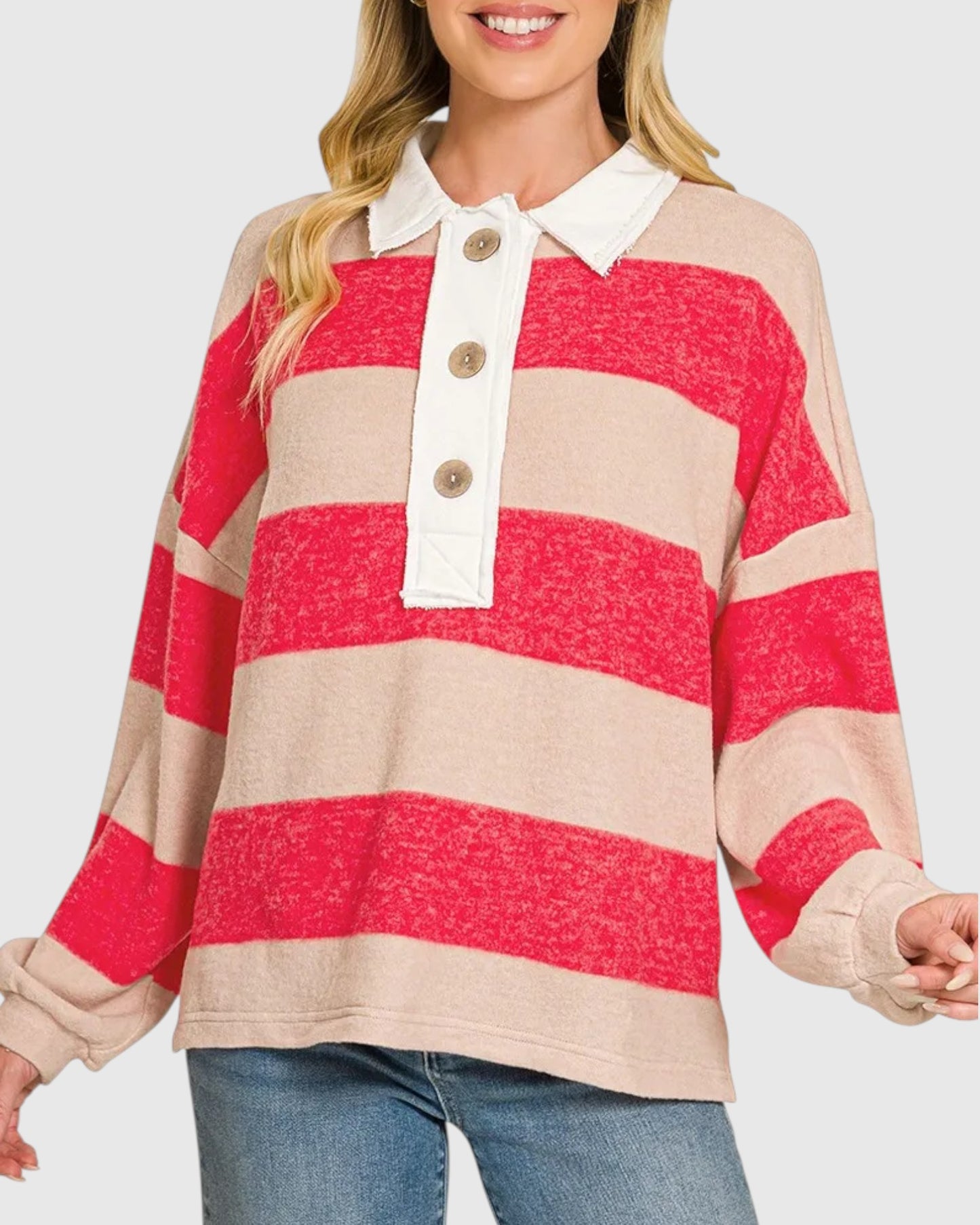 A woman wearing a long-sleeve knit polo shirt with bold horizontal stripes in bright red and warm beige, featuring a white collar and a three-button placket.