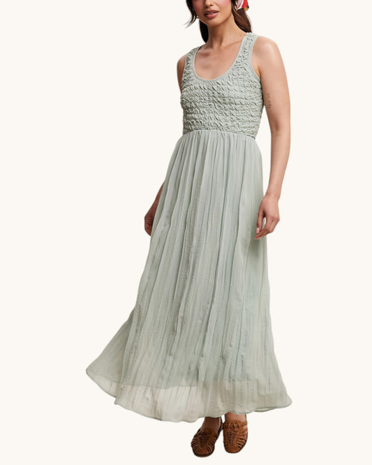 Woman wearing a light green dress with a textured bodice on a white background