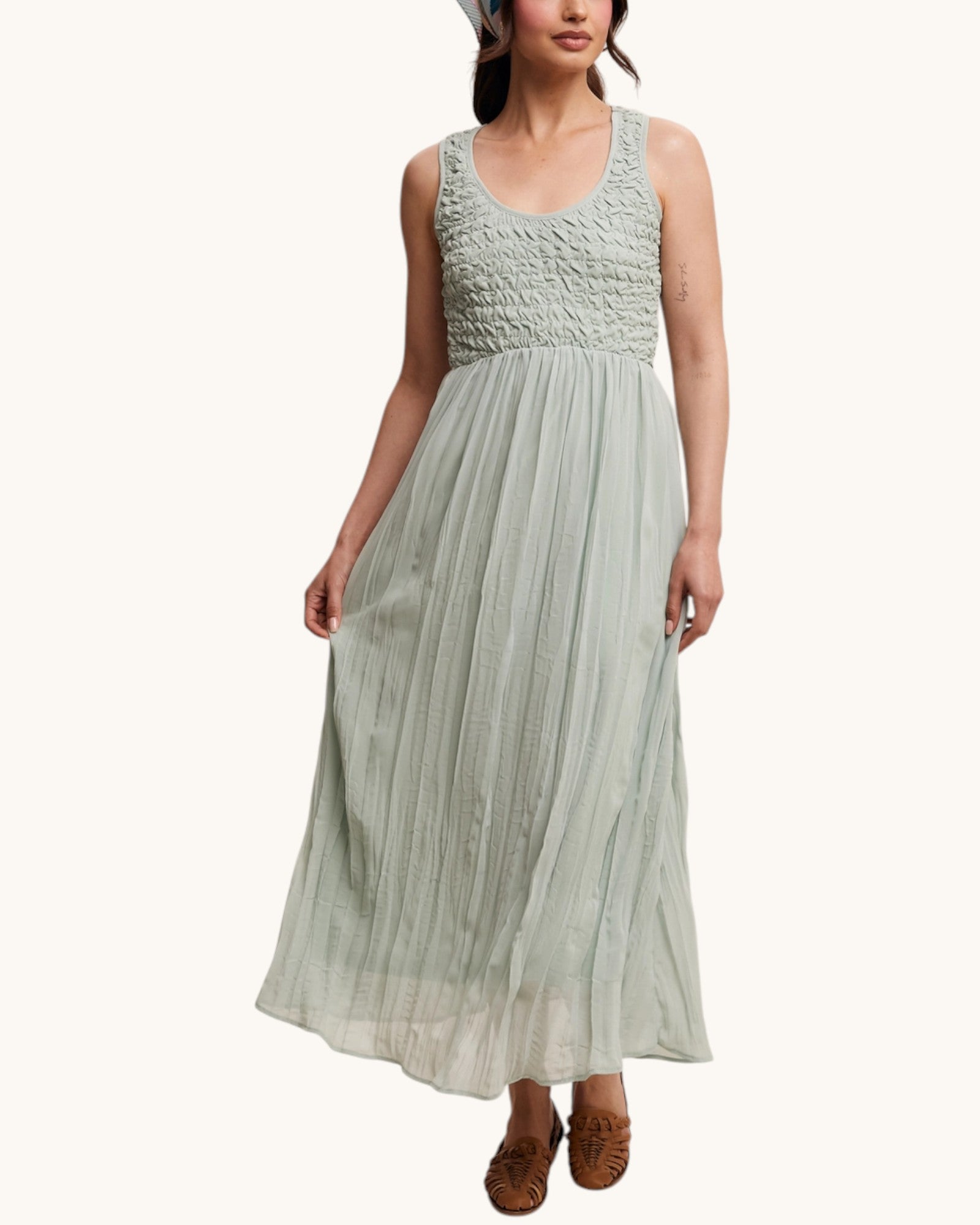 Woman wearing a light green dress with pleated bodice on a white background.