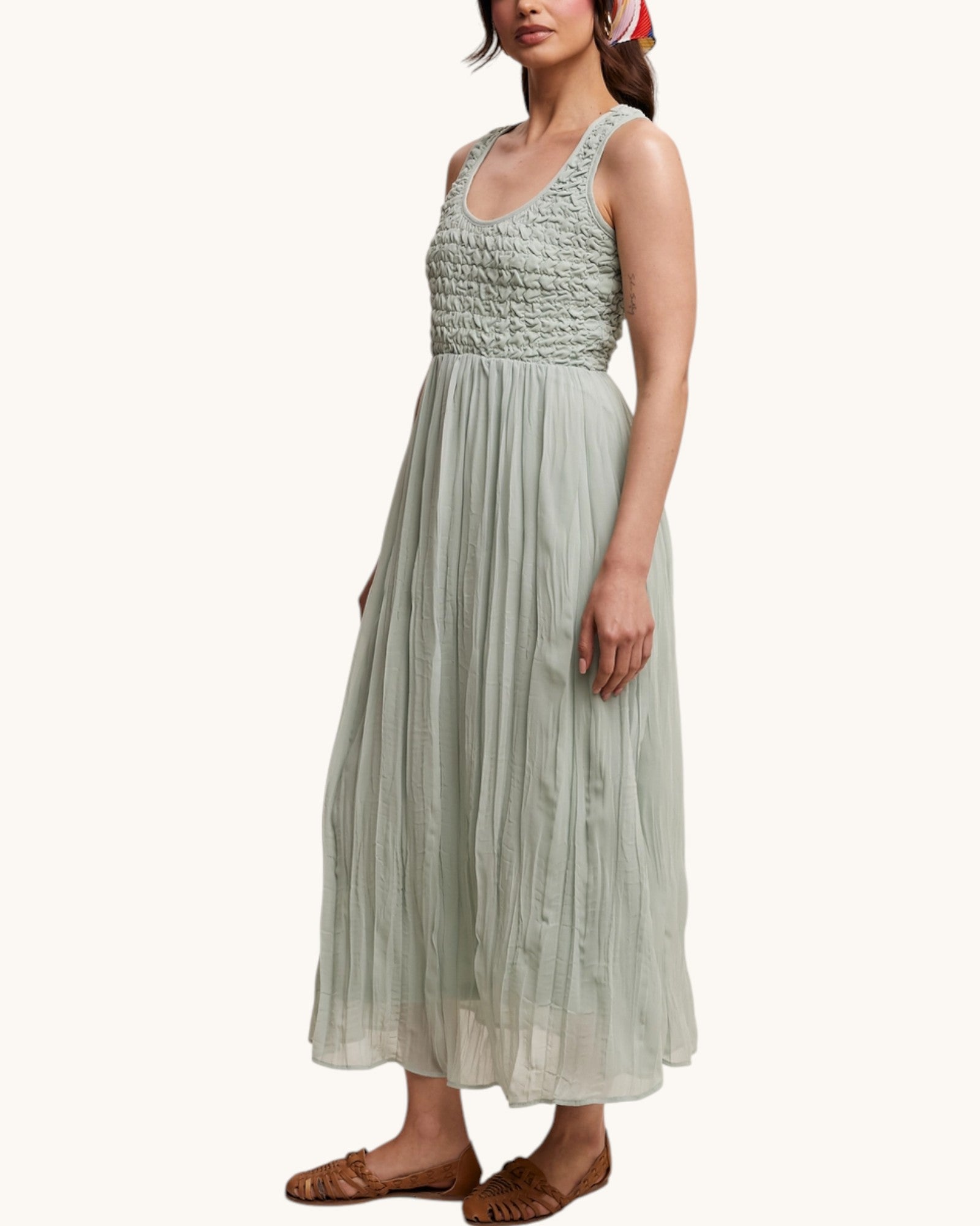 Woman wearing a light green dress with a textured bodice on a white background.