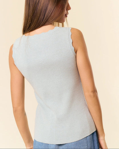 Woman wearing a light green sleeveless top against a beige background.